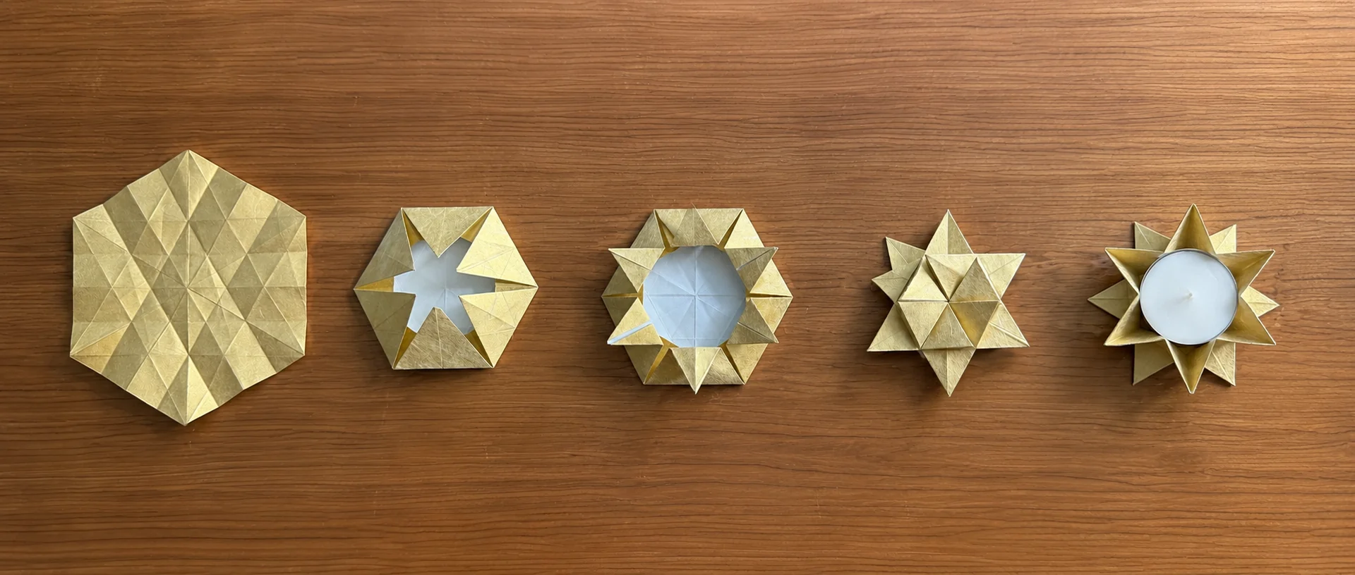 Fünf aufeinanderfolgende Entwicklungsstufen einer goldenen Origami-Arbeit bis zum fertigen Kerzenhalter